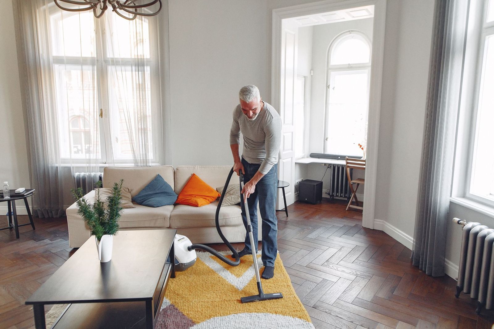 Mann saugt zu Hause den Teppich, von oben